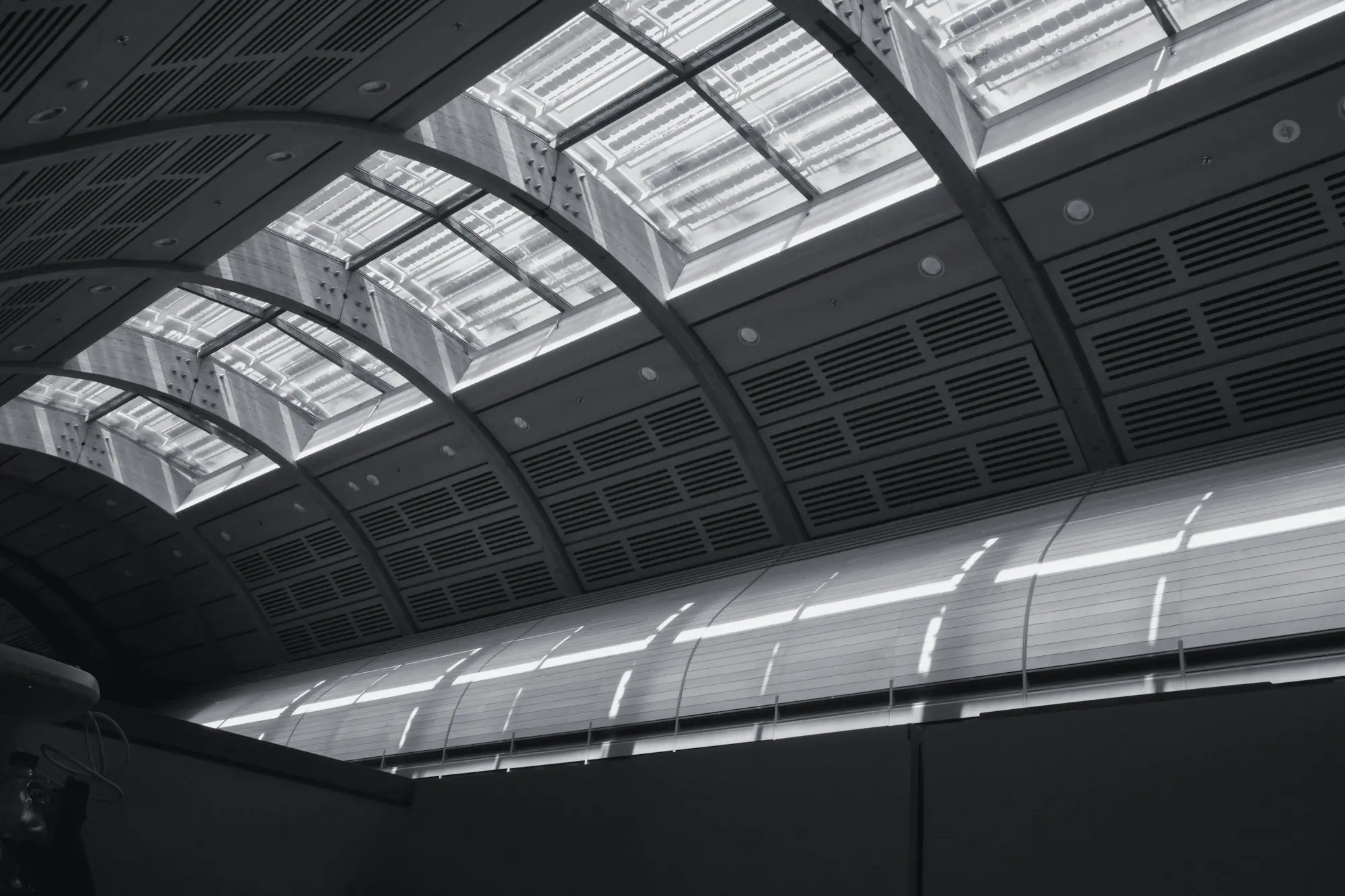 Vaulted glass roof with skylights above a dark hall