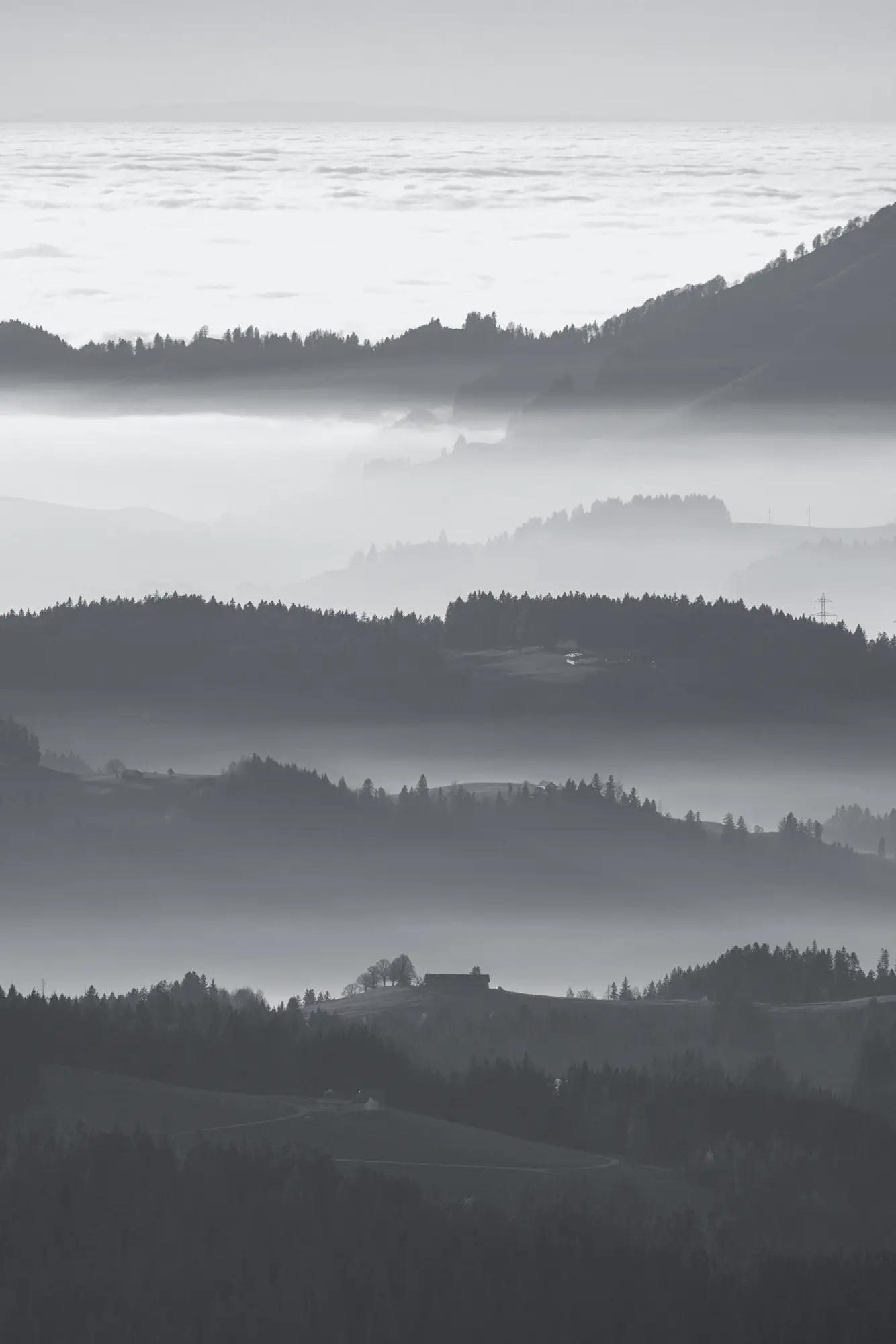 Layered ridges in fog, a single house on one of them