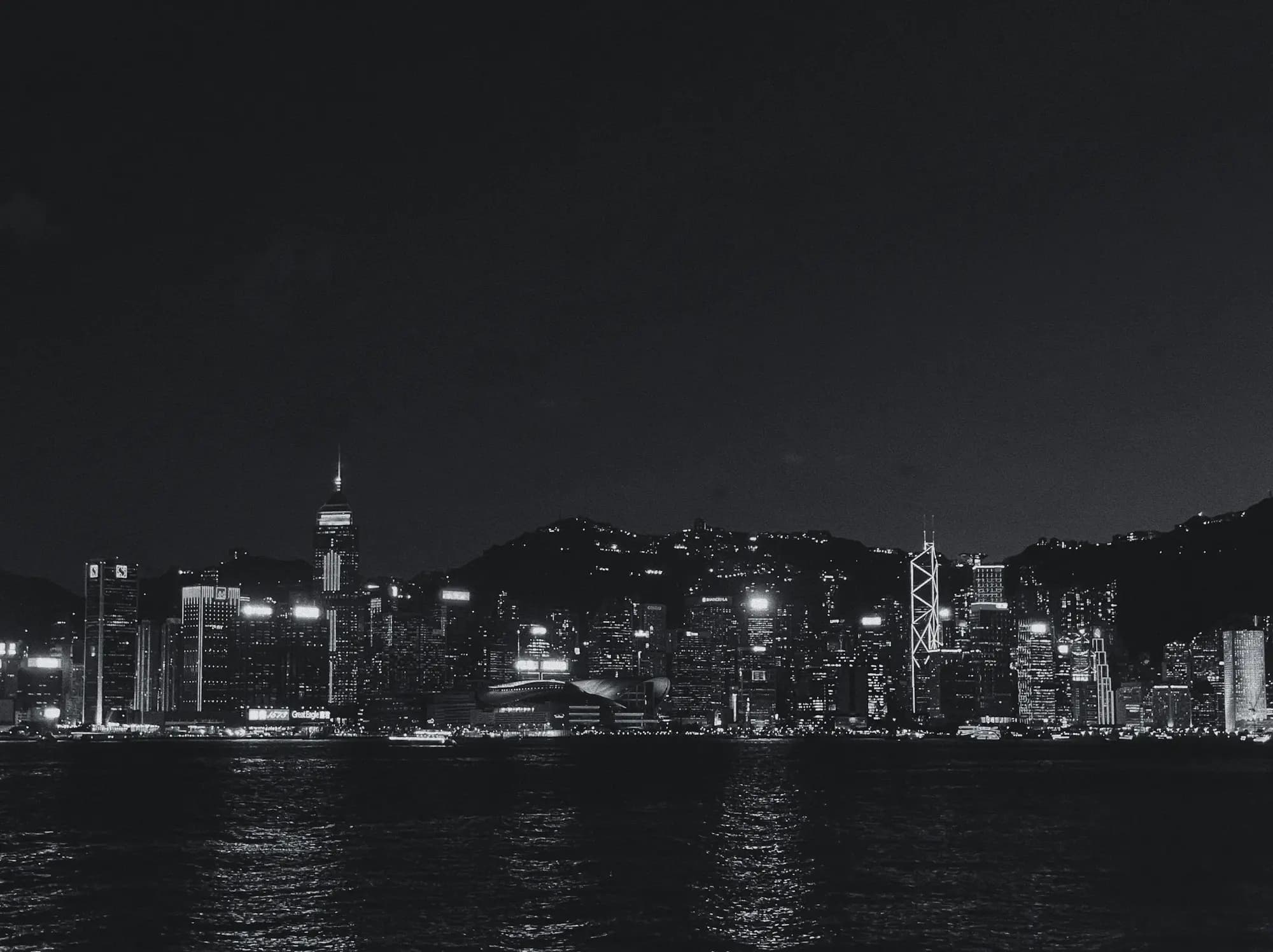 Illuminated high-rise skyline of a harbour city at night, seen from the water